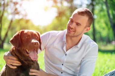 Parkta köpeği olan genç bir adam.