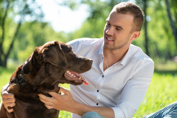 Parkta köpeği olan genç bir adam.