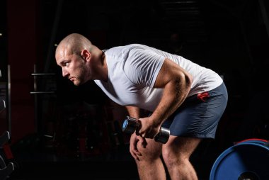 Spor salonunda dambıllarla çarpışan erkek vücut geliştirici.