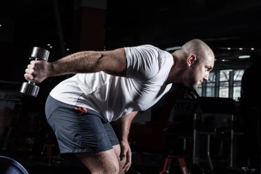 Spor salonunda dambıllarla çarpışan erkek vücut geliştirici.