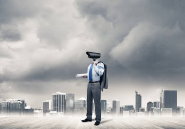 Kamera kafalı adam ahşap zeminde modern şehir manzarasına karşı duruyor.