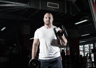 Spor salonunda dambıllarla çarpışan erkek vücut geliştirici.