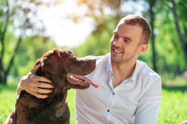Parkta köpeği olan genç bir adam.