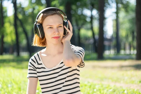 Una joven tiene música en un parque de verano. — Foto de Stock