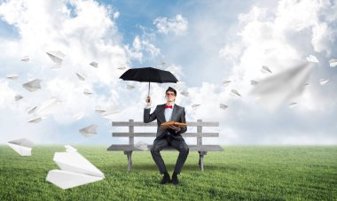 Bir bankta şemsiyesi olan genç bir iş adamı