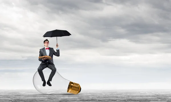 Jovem empresário com um guarda-chuva e um livro — Fotografia de Stock