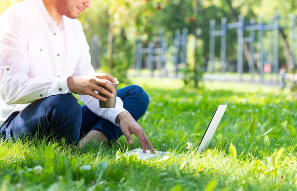 Empresário usando computador portátil na grama verde — Fotografia de Stock