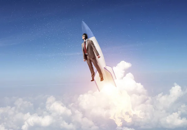 航空機の帽子をかぶったビジネスマンがロケットで飛ぶ ストック写真