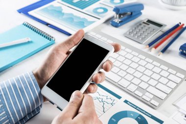 Akıllı telefonlu bir iş adamı, ofiste çalışıyor.