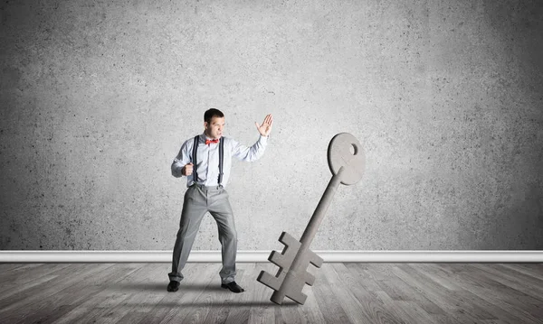 Breaking through access concept with man in room crashing concrete key — Stock Photo, Image