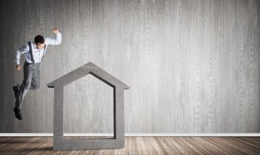 Taştan ev silueti, emlak sigortasının sembolü olarak boş odada.