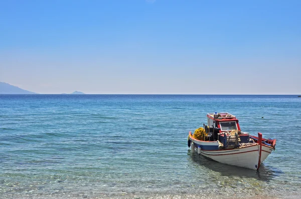그리스에 있는 빈 해변에 단일 낚시 보트 로열티 프리 스톡 사진
