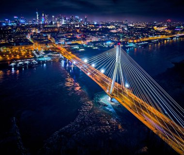 Güzel panoramik hava aracı gökyüzü manzaralı Varşova 'nın arka planında Swietokrzyski asma köprüsü var. Geceleri büyük şehrin ışıkları, Polonya..