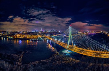 Güzel panoramik hava aracı gökyüzü manzaralı Varşova 'nın arka planında Swietokrzyski asma köprüsü var. Geceleri büyük şehrin ışıkları, Polonya..