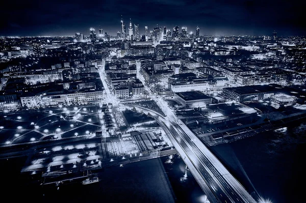 Beautiful panoramic aerial drone skyline view of the center of night Warsaw with skyscrapers in the background with the Swietokrzyski suspension bridge - the lights of the big city by night, Poland.