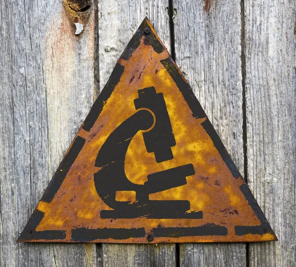Microscope Icon on Weathered Warning Sign. — Stock Photo, Image