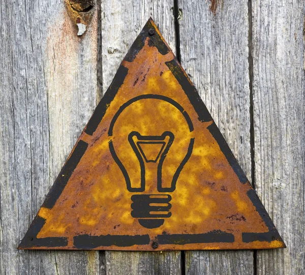 Glödlampa ikonen på rostiga varningstecken. — Stock fotografie