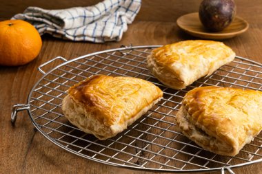 Soğutma rafında taze pişirilmiş nefis ton balığı turtası, ahşap tabakta olgun tutku meyvesi ve ahşap masada olgun portakal..