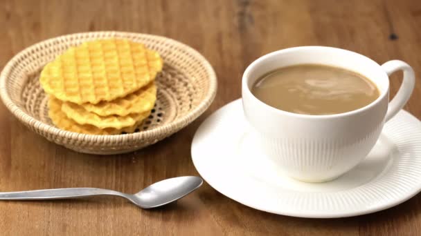 将糖倒入木桌上的热牛奶咖啡的白色陶瓷杯 用竹盘和金属勺子做的一堆脆华夫饼 — 图库视频影像