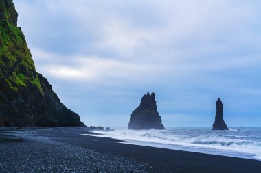 Reynisfjara Kara Kum Sahili 'nin Reynisfjall Dağı' ndaki manzarası. Fırtınalı okyanus dalgaları, Vik, İzlanda 'da yaz günü bulutlu.