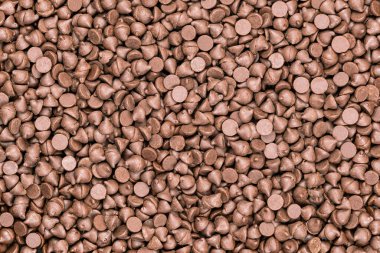 Arka planda çikolata parçacıkları yığını var. Lezzetli sütlü çikolata parçacıkları.