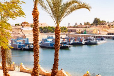 Güneşli bir günde Aswan, Yukarı Mısır 'daki Abu Simbel köyünde Nasser Gölü' ndeki tekneler ve arka planda devasa kaya kesimli tapınaklar var..