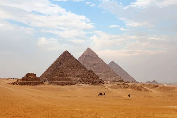 埃及开罗 雾蒙蒙的吉萨高原风光 游客和当地人骑着骆驼 背景是大金字塔 — 图库照片