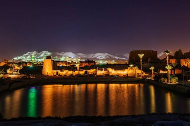 Luxor 'daki Karnak Tapınak Kompleksi' nin gece sahnesinde kutsal bir göl ve yıkılmış bir yapı, Mısır.