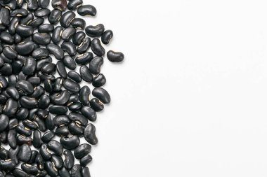 Top view of uncooked black beans on white background with copy space.