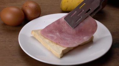 Taze jambon ve kızarmış yumurtayı beyaz seramik tabakta ahşap masaya koymak..