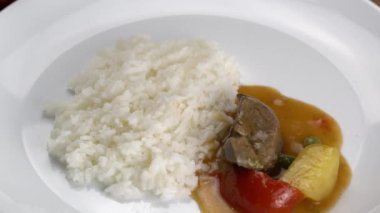 Ladling ev yapımı sığır eti güveç ile pişirilmiş yasemin pilavı ile birlikte beyaz bir seramik tabağa konur. Etli, patatesli, domatesli ve yeşil bezelyeli biftek çorbası..