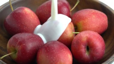 Tahta kaseye taze süt dökmek beyaz arka planda olgun, çıtır çıtır bir elma içerir..