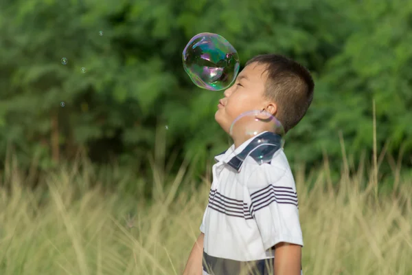 Kind spielt mit Seifenblasen. — Stockfoto