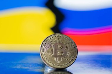 Ukrayna ve Rus bayrağının arka planında metal para Bitcoin. Ekonomik yaptırımlar kavramı.