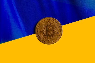 Ukrayna bayrağının arka planında Bitcoin. Ukrayna 'daki savaşın arka planına karşı kripto para piyasası kavramı.