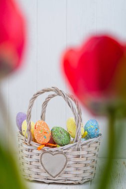 Beyaz ahşap arka planda sepette çok renkli Paskalya yumurtaları..