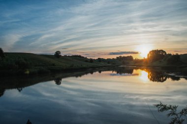 Yaz güneşli akşamları, tarla bitkileriyle birlikte göletin yanında. Ukrayna.