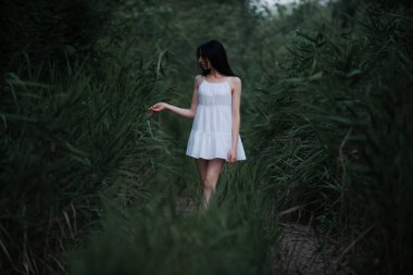 Doğada, nehrin kenarında kısa beyaz elbiseli güzel seksi kız..