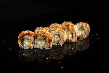 Siyah parlak arka planda suşi rulosu.