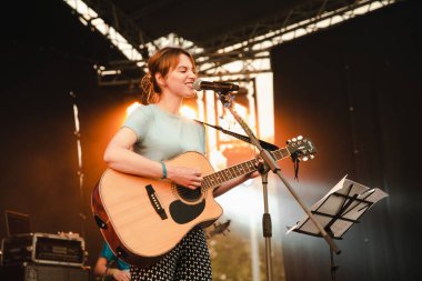 Gitarlı kız mikrofon konserinde şarkı söylüyor..