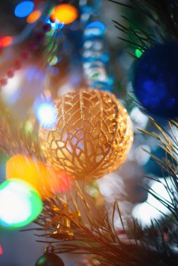 Christmas tree decorations on a blurred background with garland lights in the background.