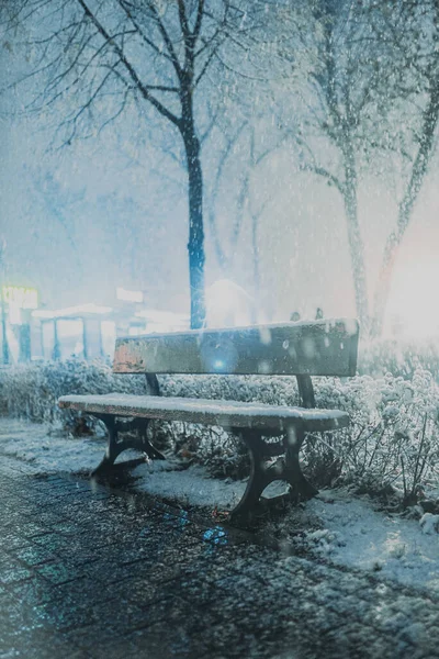 The first night snow in the night city in the light of lanterns with a blurred background.