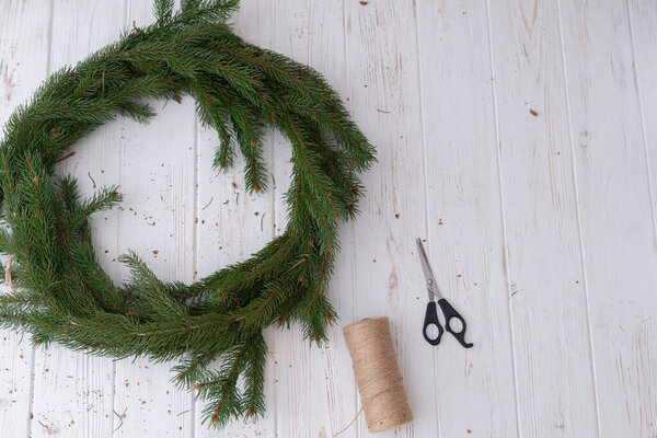 Процесс создания Рождественского венка на белом деревянном фоне.