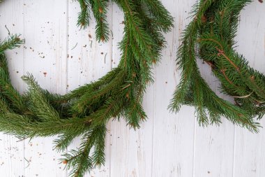 Beyaz ahşap arka planda bir Noel çelengi oluşturma süreci.