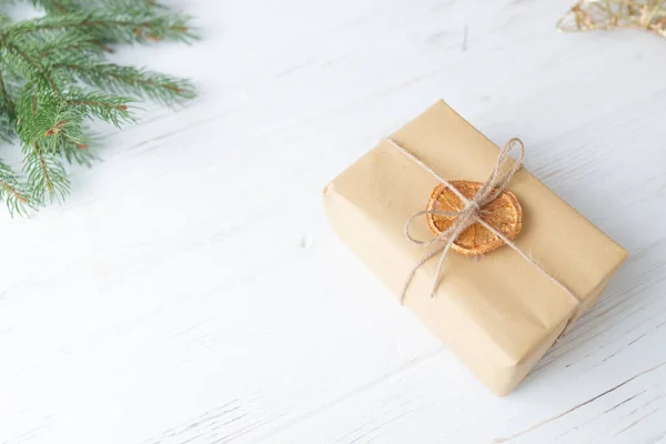 Bir adam Noel hediyesini beyaz ahşap arka planda el sanatları kağıdına sarar..