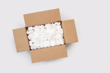 Kahverengi bir karton kutunun içinde köpük parçaları paketleniyor.