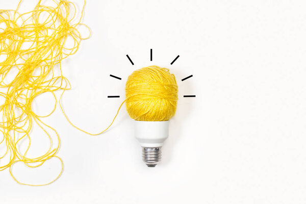 Light bulb made with a yellow thread on a white background