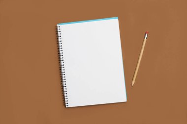 A blank notebook and a pencil on a brown background