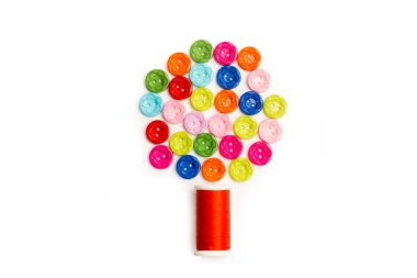Colored buttons and a thread spool in a tree shape on a white background