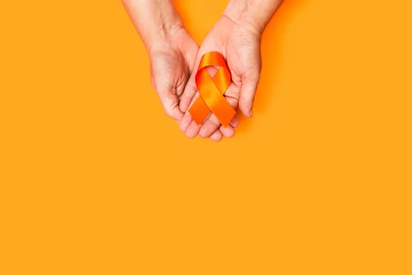 Kobieta Trzyma Pomarańczową Wstążkę Pomarańczowym Tle Przestrzenią Kopiowania — Zdjęcie stockowe